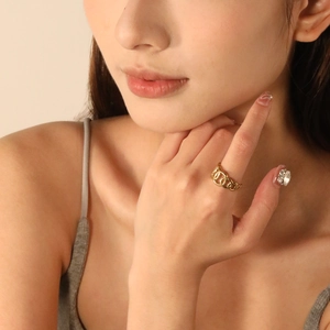Close-up of a 18K gold-plated interlocking chain ring on a finger with stylish nails