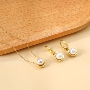 Detail of elegant gold-plated necklace and pearl earrings set on a wooden tray