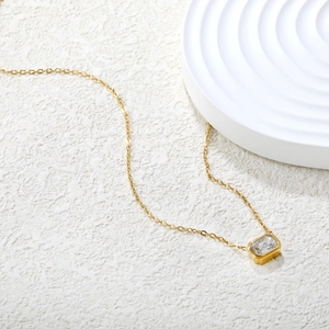 Detalle de collar de acero inoxidable dorado de 18K con colgante de circón corte esmeralda