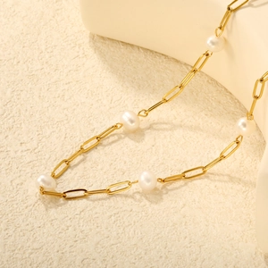 Gros plan d'un collier à maillons trombone dorés orné de cinq perles d'eau douce blanches