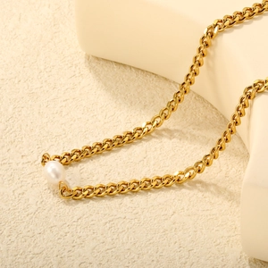 Détail macro du collier chaîne gourmette en or 18K avec une perle d'eau douce blanche