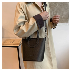 Detailed view of black litchi pattern leather bucket bag with elegant stitching and strap