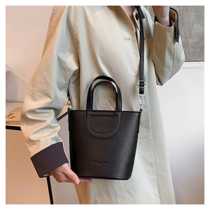 Detail of black lychee grain leather bucket bag featuring silver hardware and U-shaped stitching