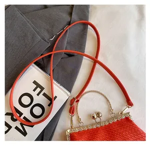 Detailed view of woven orange texture and gold engraved frame with pearl clasp closure