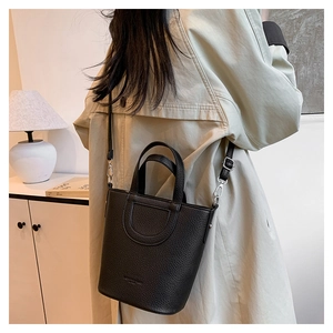 Detail of black lychee grain leather bucket bag with U-shaped stitching and adjustable strap