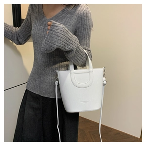 Detail view of white bucket bag featuring litchi grain texture and D-shaped silver buckle