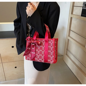 Dettaglio della borsa da sposa rossa con motivo Xi e fiocco decorativo in nastro