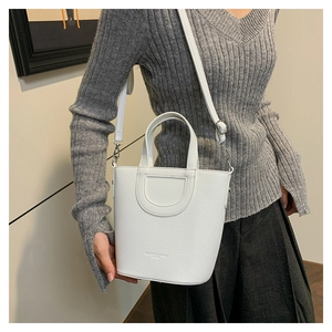 Detailed shot of white lychee leather bucket bag with D-shaped stitching and top handle