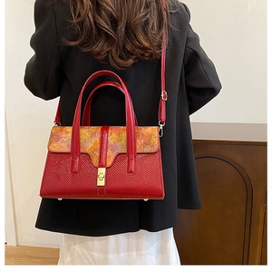 Detail of red embossed leather handbag with vintage floral silk flap and gold twist lock