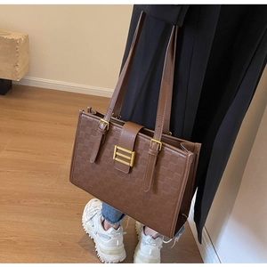Detail of brown checkered tote bag with adjustable straps and golden metal buckle