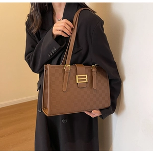 Detail view of brown checkered tote bag with gold hardware and smooth leather straps