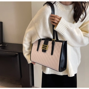 Close-up of pink checkered tote bag with gold buckle detail and black leather straps