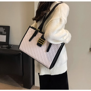 Detail of checkered woven tote bag with black leather handles and gold buckle accent