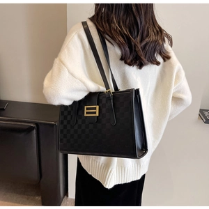 Detail shot of a black checkered tote bag with gold buckle on model's shoulder