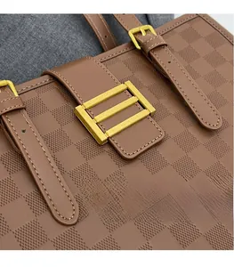 Close-up of brown leather tote featuring checkered embossing and golden hardware buckle