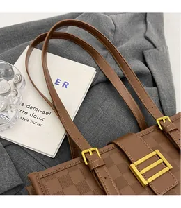 Close-up of brown checkered tote bag with golden metal lock on a stylish blazer