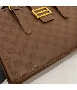 Detailed close-up of brown checkered textured leather tote bag with gold metal buckle