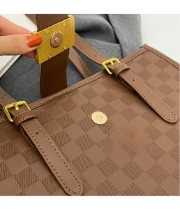 Detail of gold magnetic buckle on brown checkered tote bag with leather strap