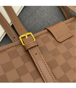 Macro shot of gold-tone buckle and checkerboard embossed leather on brown tote bag