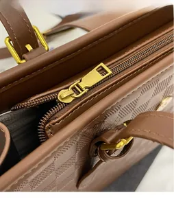 Macro detail of glossy gold hardware zipper and textured brown leather tote bag