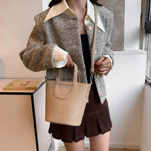 Elegant beige pebbled leather bucket bag with top handle and adjustable shoulder strap