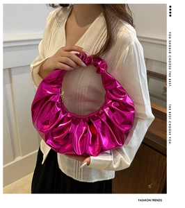 Dettaglio di borsa a mezzaluna plissettata rosa metallizzato portata da una modella