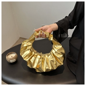 Dettaglio della borsa a mano dorata plissettata con elegante nodo sul manico