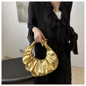 Dettaglio borsa a mano dorata metallizzata con trama a pieghe e design a mezzaluna