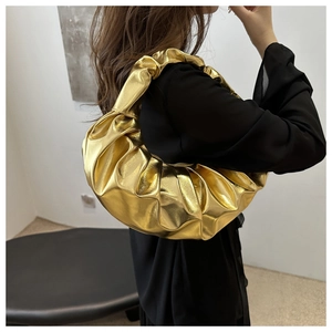 Dettaglio della borsa a spalla plissettata in oro metallizzato con texture a nuvola