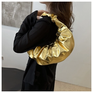 Primo piano della borsa a mezzaluna plissettata oro metallizzato indossata da una modella