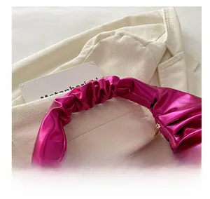 Dettaglio di borsa a mano plissettata rosa metallizzato con manico arricciato e zip