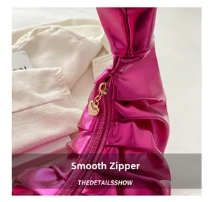 Dettaglio borsa a mano plissettata rosso rosa lucido con zip e ciondolo a cuore oro