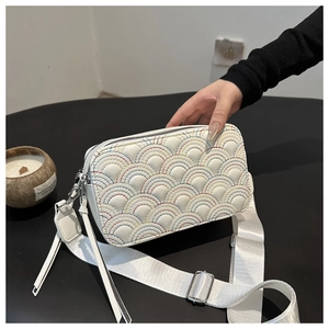 Detail of white camera bag with rainbow arch stitching and leather tassel ornament