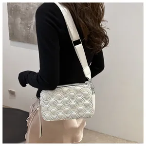 Detail of white leather bag featuring colorful rainbow embroidery and wide strap