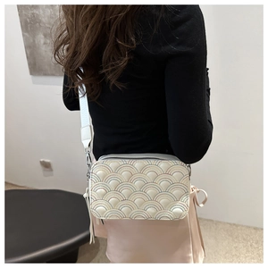Detailed view of cream camera bag with colorful embroidery and a wide textile strap