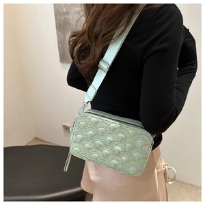 Detail view of mint green crossbody camera bag with rainbow stitching and wide strap