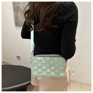 Detail of light green quilted camera bag with rainbow stitching and wide strap