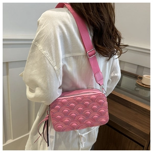 Close-up of pink quilted crossbody bag featuring rainbow stitching and wide nylon strap