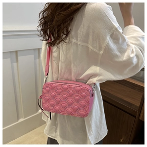 Detailed close-up of pink camera bag featuring quilted rainbow scale stitching and metal hardware