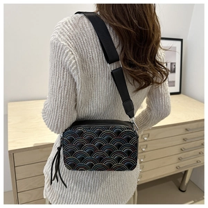 Close-up of black crossbody camera bag with rainbow stitching and wide strap on model