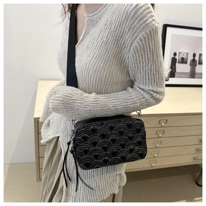Detailed view of black rainbow quilted crossbody bag with stylish wide woven strap