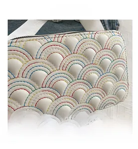 Close-up of white leather camera bag featuring colorful rainbow stitching and zip detail