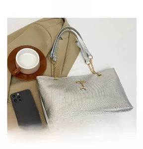 Detail of silver crocodile pattern tote bag with gold chain strap and deer charm