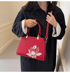 Detail of red leather handbag featuring exquisite floral embroidery and golden hardware