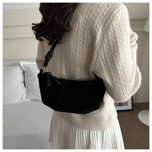 Détail du sac à main noir en daim avec un nœud élégant sur la bandoulière réglable