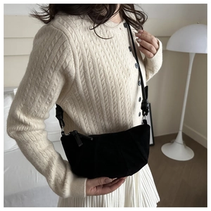Detail of a large black crescent crossbody bag with a knotted strap on a model