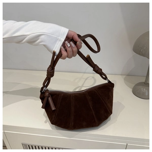 Detail of dark brown suede crescent bag featuring pleated texture and decorative knots