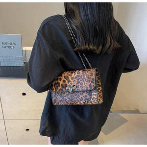 Close-up of leopard print bag with metal chain strap worn over a black outfit