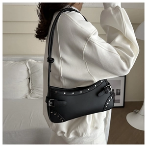 Close-up of black leather underarm bag with silver studs and metal buckle detail