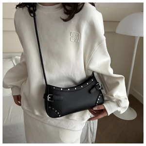 Detail of black matte leather half-moon bag featuring silver studs and buckle straps